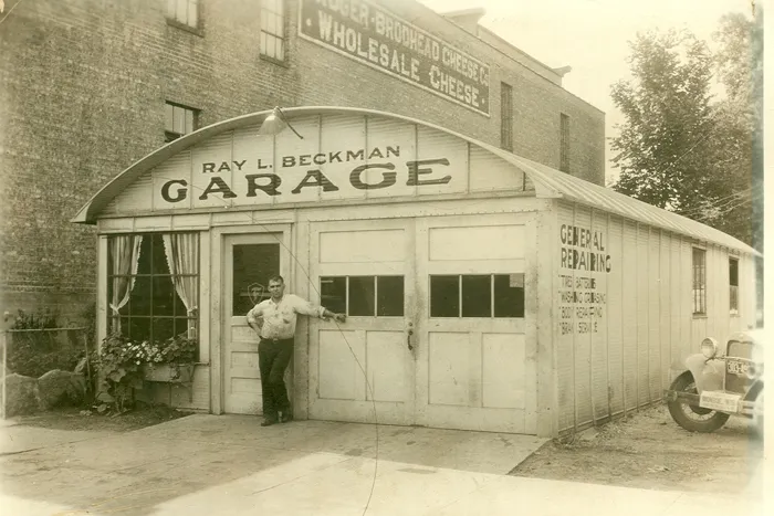 Old steel building with a man outside posing for the camera