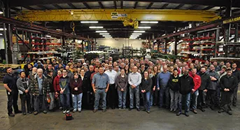 Large group of factory employees standing together inside a manufacturing warehouse facility